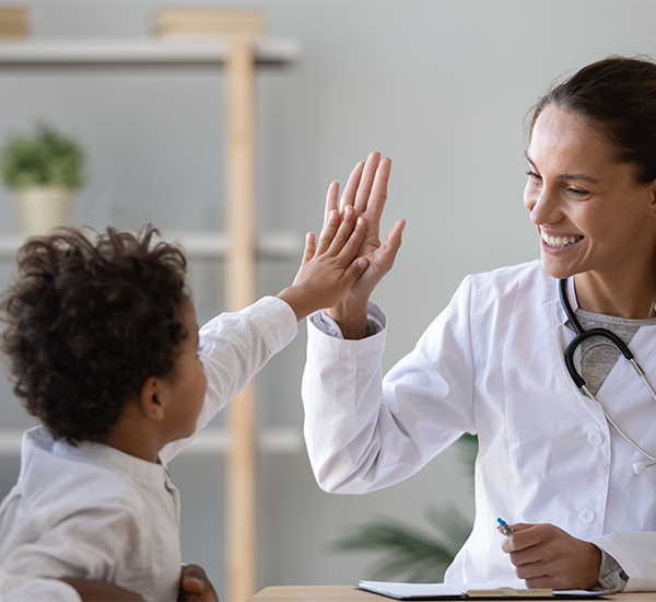 Female doctor smiling and high-fiving a young patient