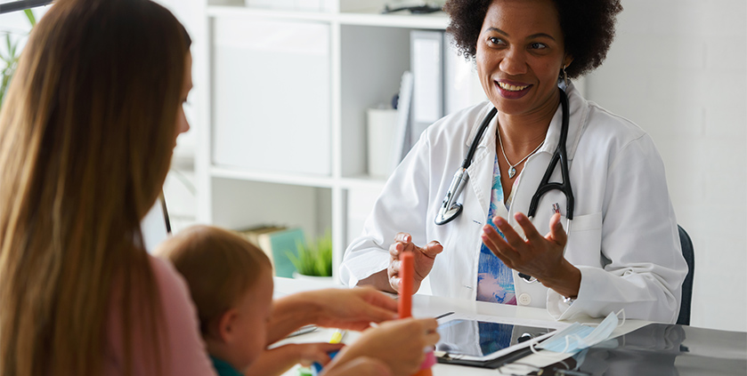 African American doctor talking to young mother with her child