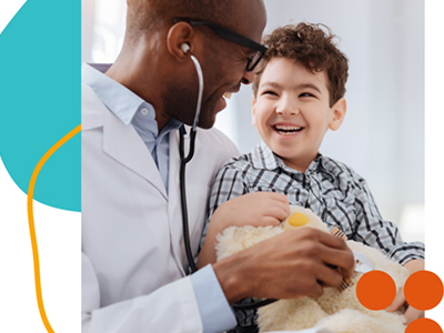 African american doctor smiling and looking at young child holding a teddy bear